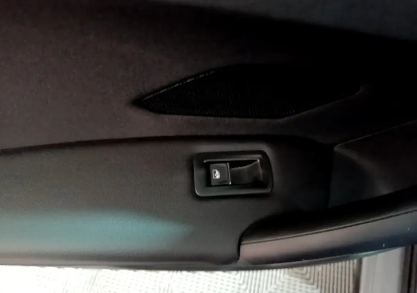 Détail du bouton d'ouverture électrique du coffre sur le panneau intérieur du hayon du Volkswagen Tiguan gris foncé 2021.