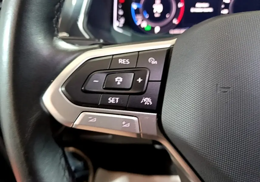 Gros plan sur les commandes de régulateur de vitesse au volant cuir du Volkswagen Tiguan gris foncé 2021.