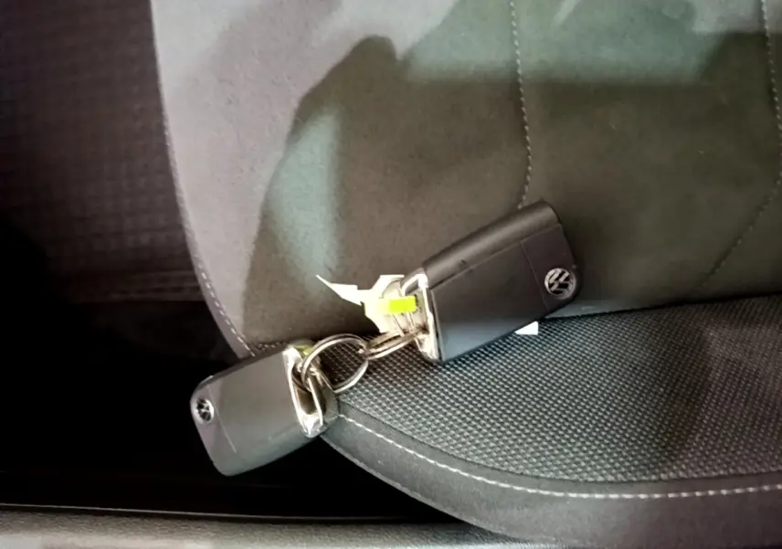 Gros plan sur deux clés Volkswagen noires posées sur un siège tissu gris foncé à surpiqûres blanches.