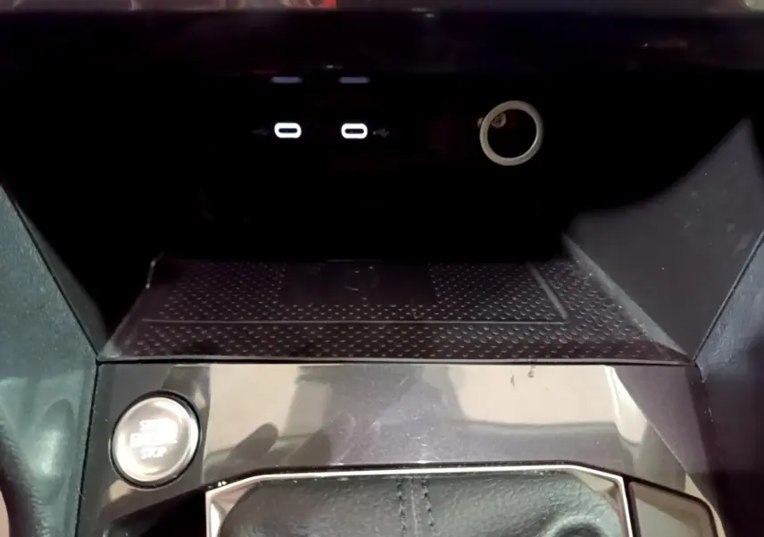 Gros plan sur la console centrale du Volkswagen Tiguan gris foncé, avec bouton démarrage et ports USB visibles.