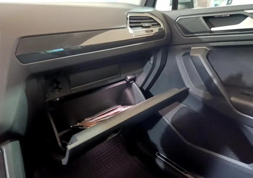 Intérieur du Volkswagen Tiguan 2021, vue côté passager sur la boîte à gants ouverte et tableau de bord gris foncé.