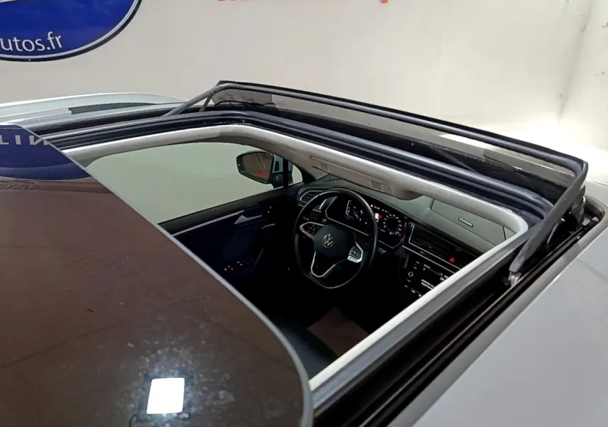 Vue plongeante sur l'intérieur noir et gris du Volkswagen Tiguan 2021 via son toit ouvrant panoramique ouvert.