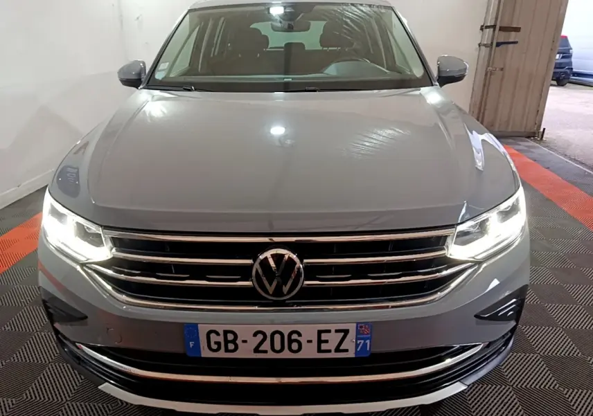 Vue avant d'un Volkswagen Tiguan gris foncé avec phares LED allumés dans un garage fermé.