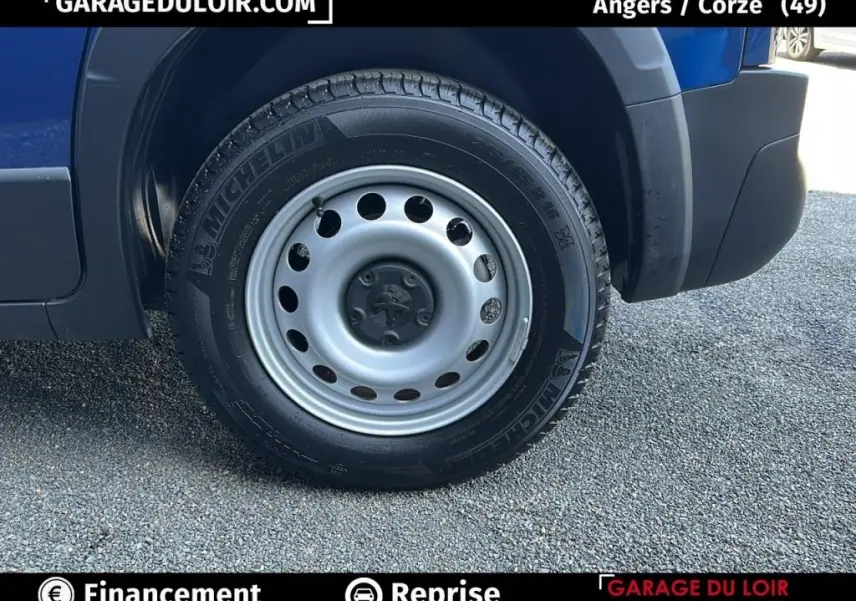 Gros plan sur la roue avant droite du Peugeot Rifter bleu 2024, mettant en valeur la jante acier et le pneu Michelin.