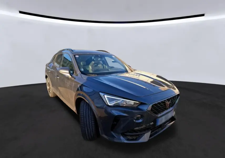 Vue 3/4 avant droite d'un CUPRA Formentor gris foncé 2023 avec calandre distinctive et phares LED anguleux.