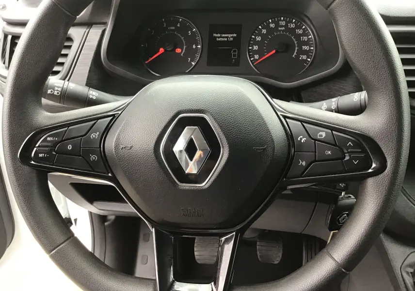 Vue rapprochée du volant noir avec logo Renault et tableau de bord du Trafic Fourgon blanc 2024.