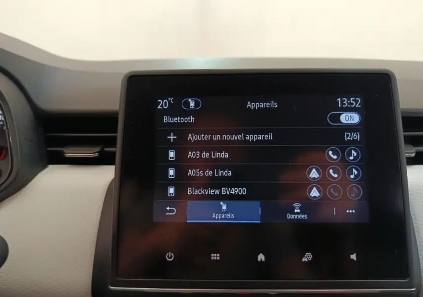 Écran tactile central de la Renault Clio blanc, affichant le menu Bluetooth avec plusieurs appareils connectés.