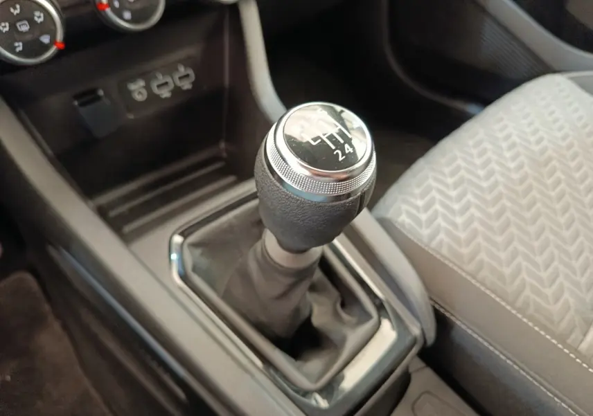 Gros plan sur le levier de vitesses manuel noir et argenté à côté du siège conducteur gris de la Renault Clio Evolution TCe 100 GPL.