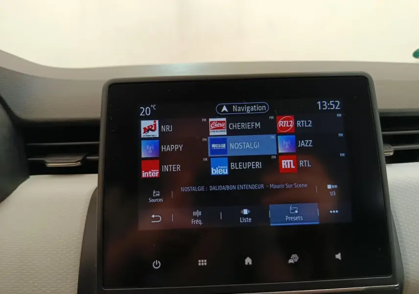 Écran tactile central de la Renault Clio 2023 affichant les stations radio avec navigation, vue intérieure frontale.
