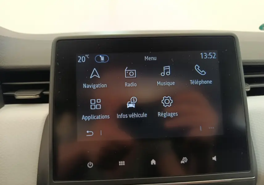 Écran tactile central de la Renault Clio blanc 2023 affichant le menu navigation, radio, musique et téléphone.