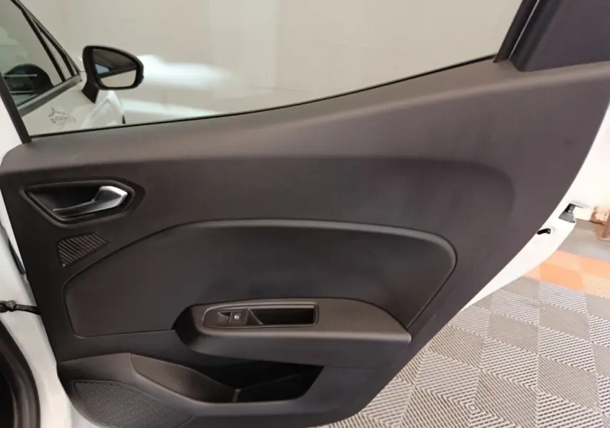 Vue intérieure de la porte arrière droite noire de la Renault Clio blanche Evolution TCe 100 GPL 2023.