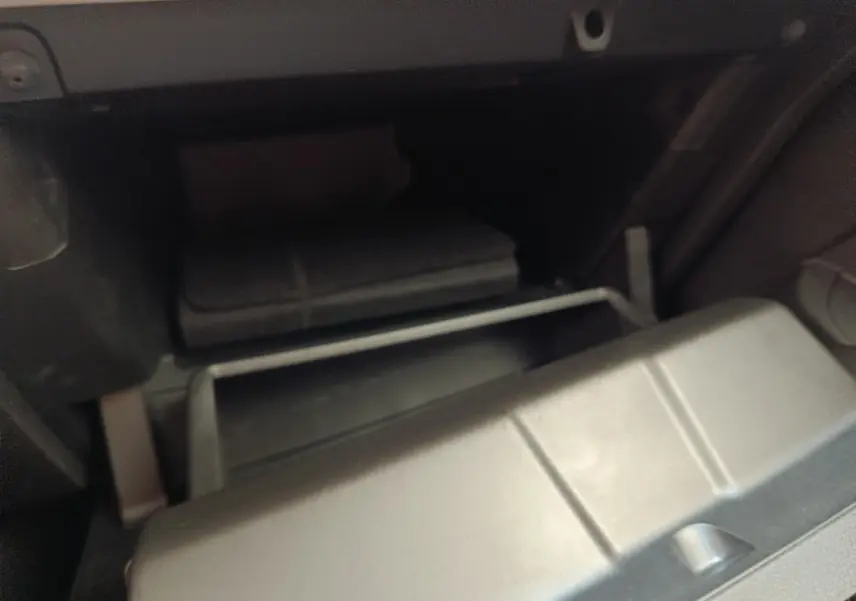 Gros plan sur la boîte à gants ouverte de la Renault Clio blanche, montrant un compartiment de rangement intérieur.