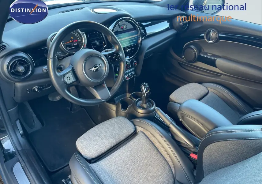 Intérieur de la MINI Cabriolet F57 2023 vu côté conducteur, sièges tissu gris et cuir noir, tableau de bord moderne avec écran central.