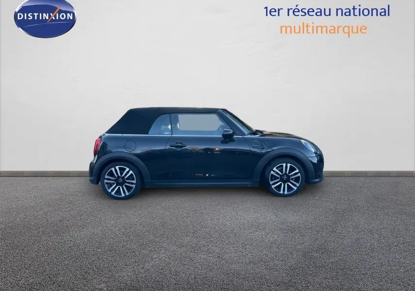 Profil côté gauche d'une MINI Cabriolet F57 noire Midnight Metal avec capote fermée, jantes bi-ton et deux portes visibles.