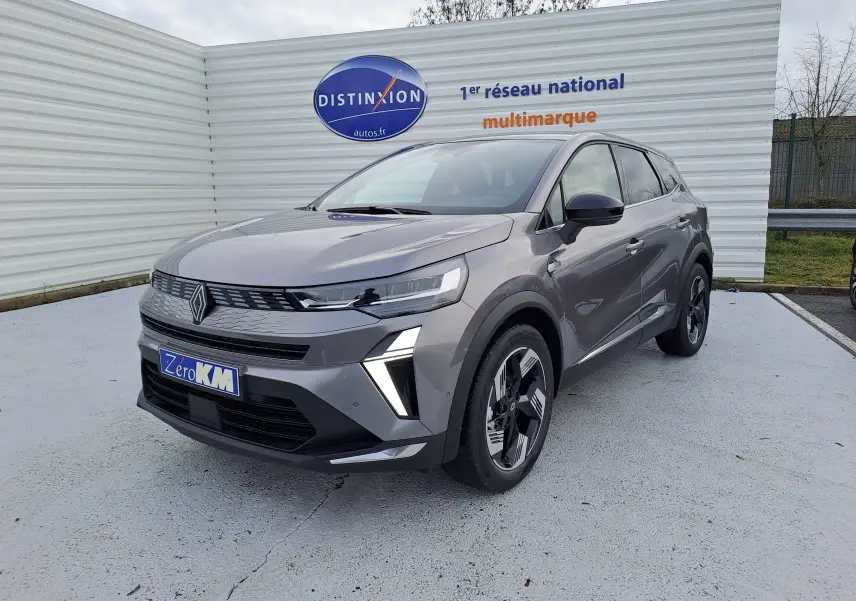 Vue de face d'une Renault Symbioz gris cassiopée avec feux LED allumés sur un parking extérieur.
