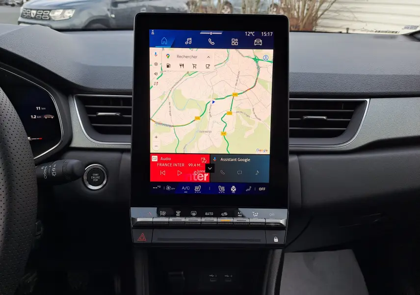 Vue intérieure centrée sur l'écran tactile vertical du tableau de bord du Renault Symbioz gris Cassiopée, avec commandes climatisation en dessous.