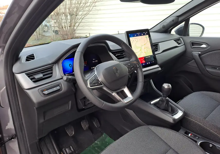 Vue intérieure côté conducteur de la Renault Symbioz gris Cassiopée, volant multifonction et écran tactile vertical.