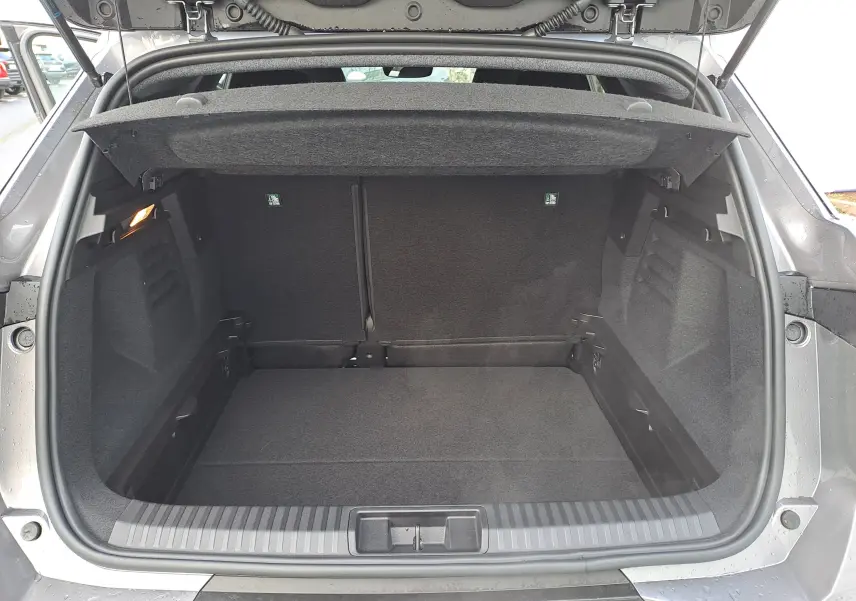 Coffre ouvert vu de l'arrière d'une Renault Symbioz gris cassiopée, montrant l'espace de chargement vide et l'habillage intérieur noir.