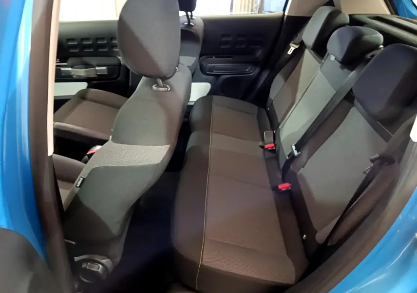 Vue intérieure côté droit sur les sièges arrière gris foncé d'une Citroën C3 bleu 2017 avec portières ouvertes.