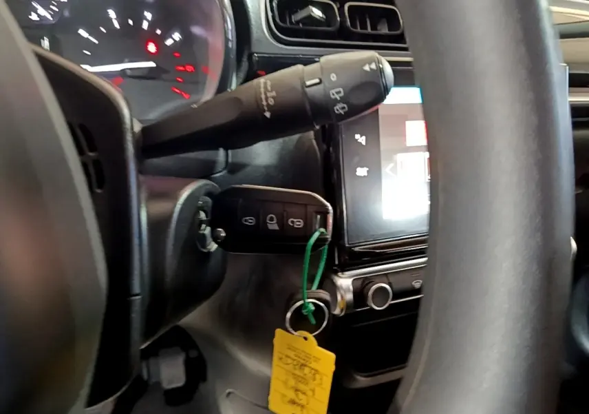 Vue rapprochée de l’intérieur de la Citroën C3 bleu, montrant le volant, le tableau de bord et la clé insérée dans le contact.