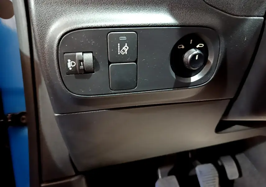 Vue rapprochée des commandes de réglage des phares et des rétroviseurs côté conducteur d'une Citroën C3 bleu 2017.