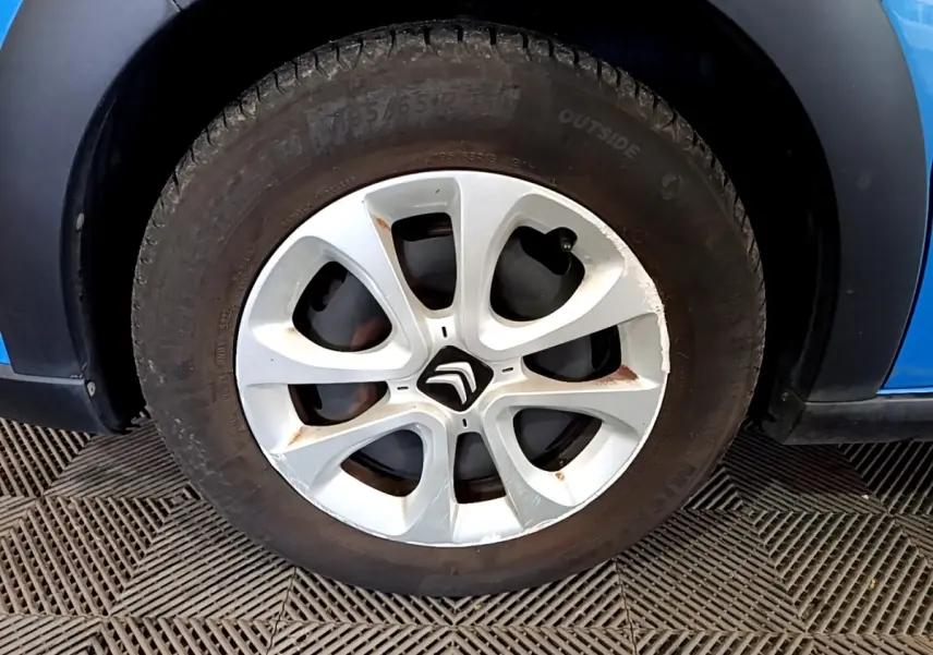 Gros plan sur la roue avant gauche d'une Citroën C3 bleu 2017 avec jante en alliage et logo Citroën central.