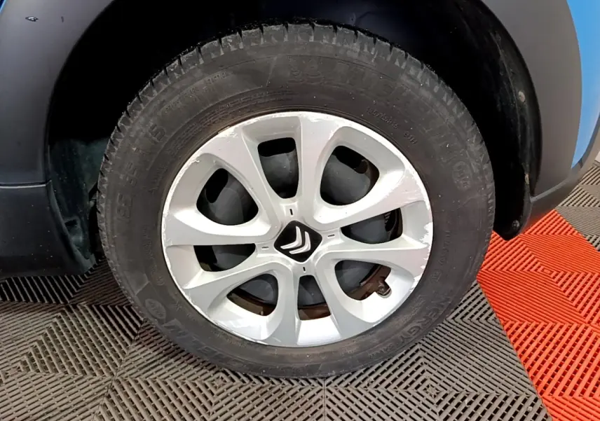 Gros plan sur la roue avant gauche d'une Citroën C3 bleue avec jante argentée et logo Citroën central.