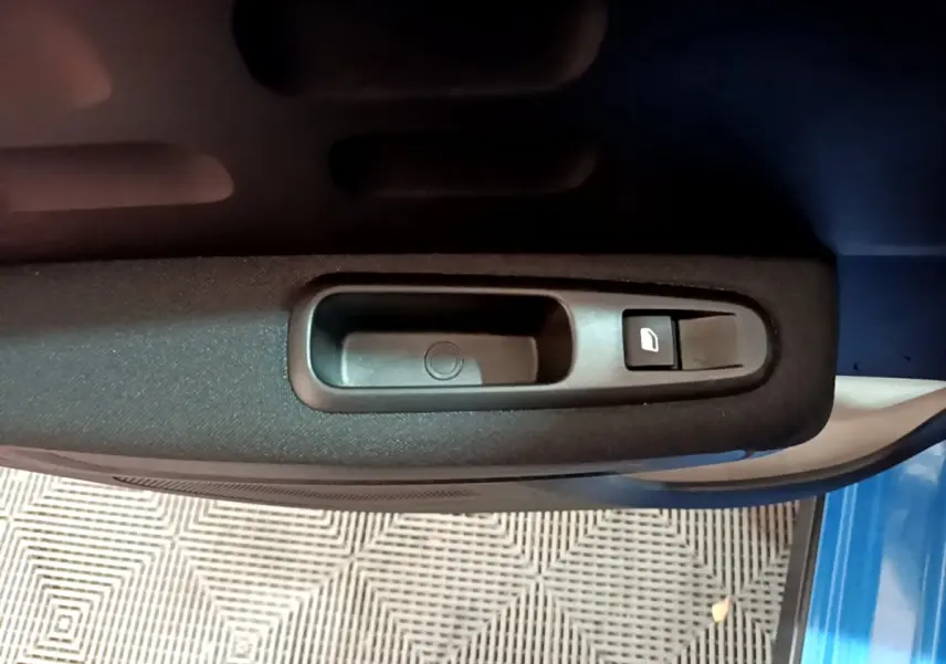 Poignée intérieure de porte côté gauche d'une Citroën C3 bleu 2017 avec bouton de commande de vitre électrique.
