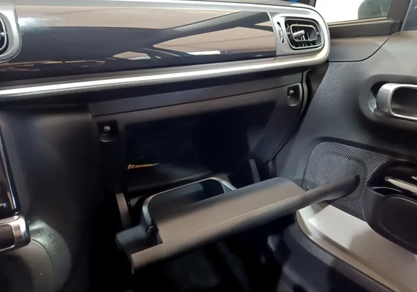Intérieur de la Citroën C3 2017, vue du côté passager avec boîte à gants ouverte et tableau de bord noir brillant.