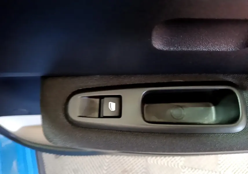 Gros plan sur la commande de lève-vitre côté conducteur d'une Citroën C3 bleu 2017.