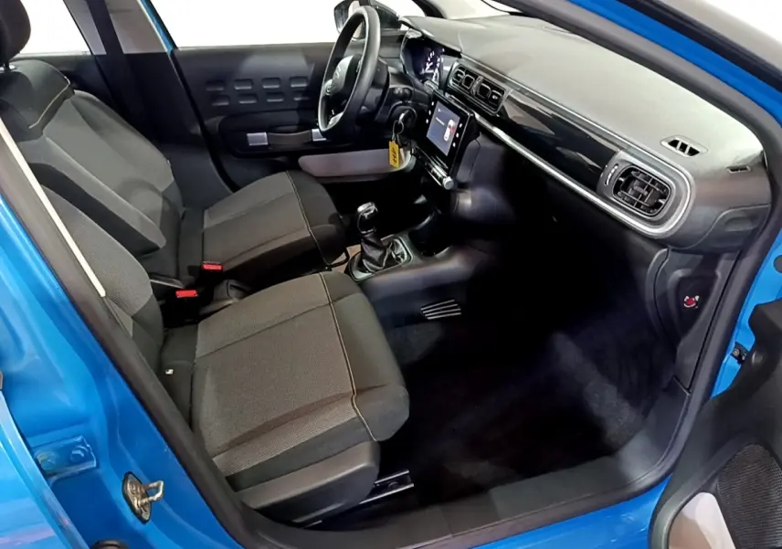 Vue intérieure côté conducteur d'une Citroën C3 bleu 2017 avec tableau de bord noir et écran tactile central.