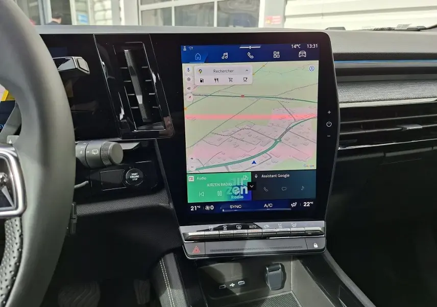 Vue intérieure centrée sur l'écran tactile vertical du tableau de bord du Renault Austral gris schiste, avec commandes climatisation visibles.