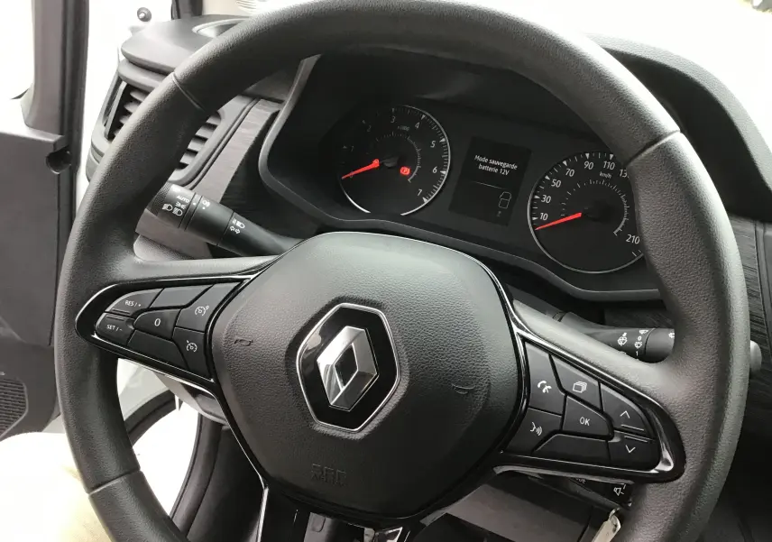 Vue rapprochée du volant noir du Renault Trafic Fourgon 2024 avec commandes intégrées et tableau de bord visible.