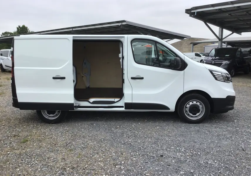 Vue latérale droite du Renault Trafic Fourgon blanc 2024 avec porte coulissante ouverte montrant l'intérieur vide en bois.