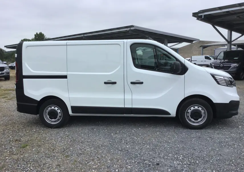 Vue de profil côté gauche d’un fourgon blanc Renault Trafic L1H1 2024 avec portes latérales et jantes acier simples.