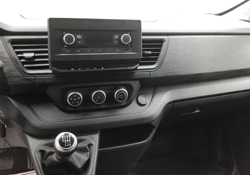 Intérieur du Renault Trafic Fourgon blanc 2024, vue centrale sur la console avec boîte manuelle et commandes de climatisation.