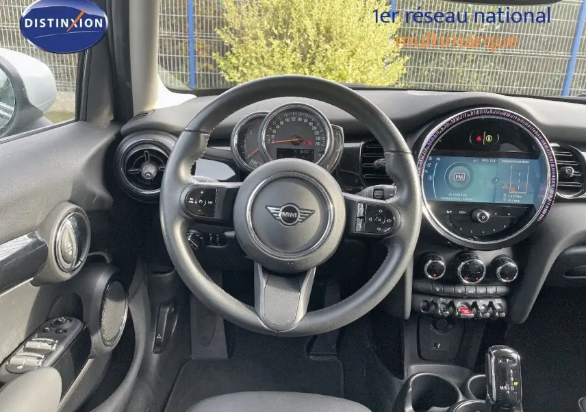 Vue intérieure avant du poste de conduite d'une MINI noire avec volant multifonctions et écran tactile circulaire.