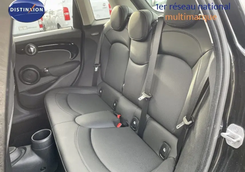 Vue intérieure côté droit sur la banquette arrière en cuir noir d'une MINI 2023 noir Midnight Metal avec ceintures de sécurité visibles.