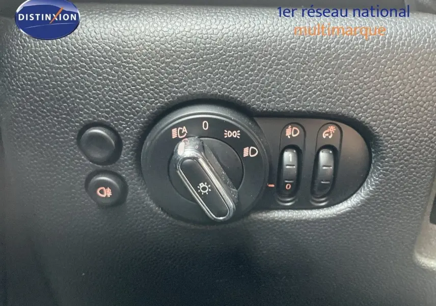 Gros plan sur les commandes d'éclairage et réglages du tableau de bord d'une MINI noire Midnight Metal 2023.