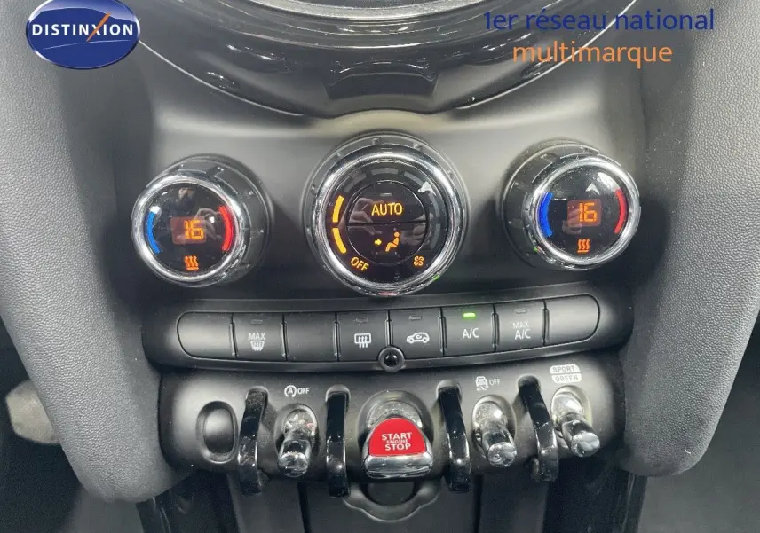 Gros plan sur la console centrale de la MINI 2023 noir midnight metal, avec commandes climatisation et bouton start/stop rouge.