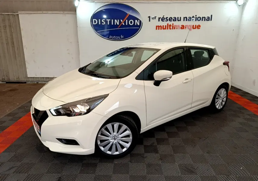 Nissan Micra blanche vue en 3/4 avant droit dans un showroom avec éclairage intérieur et logo Distinxion.