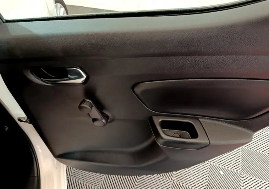Vue rapprochée de la porte intérieure côté gauche d'une Nissan Micra blanche, avec manivelle de vitre manuelle.