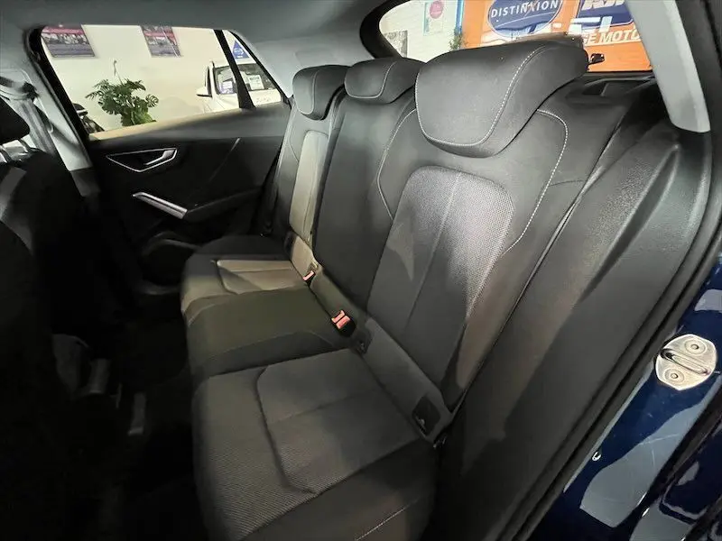 Vue intérieure arrière droite des sièges noirs du coffre de l'Audi Q2 30 TFSI S-Line bleu Navarre 2021.