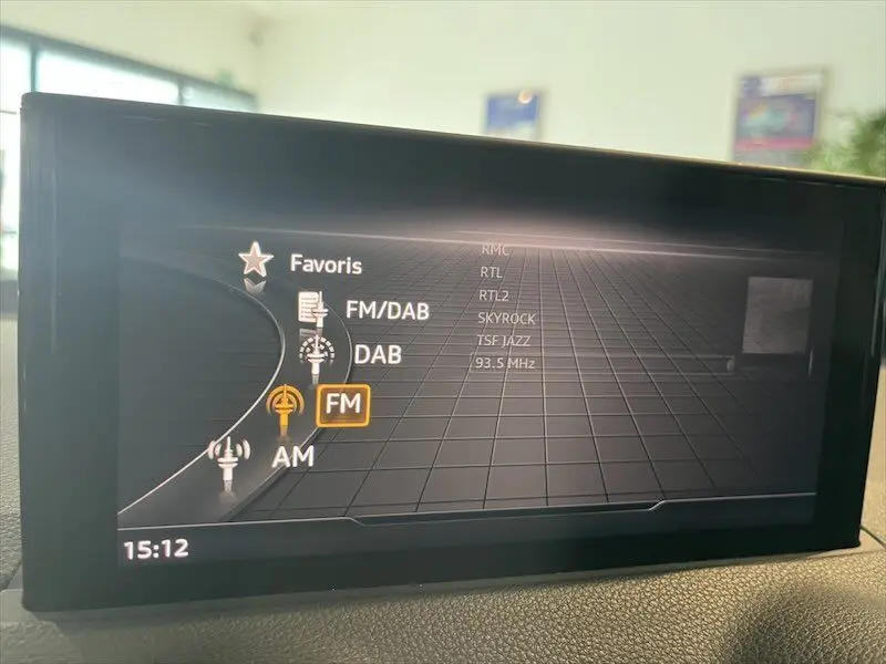 Écran multimédia intérieur de l'Audi Q2 bleu Navarre S-Line 2021 affichant les options radio FM/DAB en vue frontale.