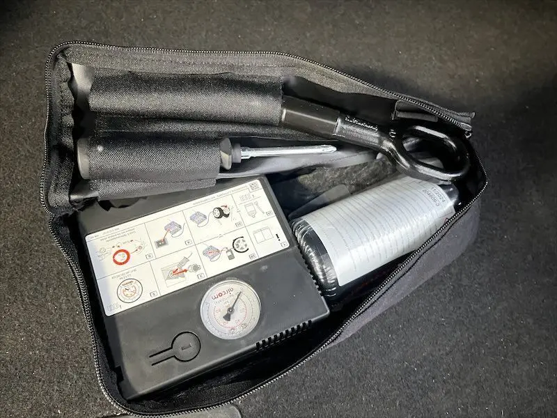 Gros plan sur le kit de réparation pneumatique dans le coffre d'un Audi Q2 bleu Navarre métal 2021 S-Line.