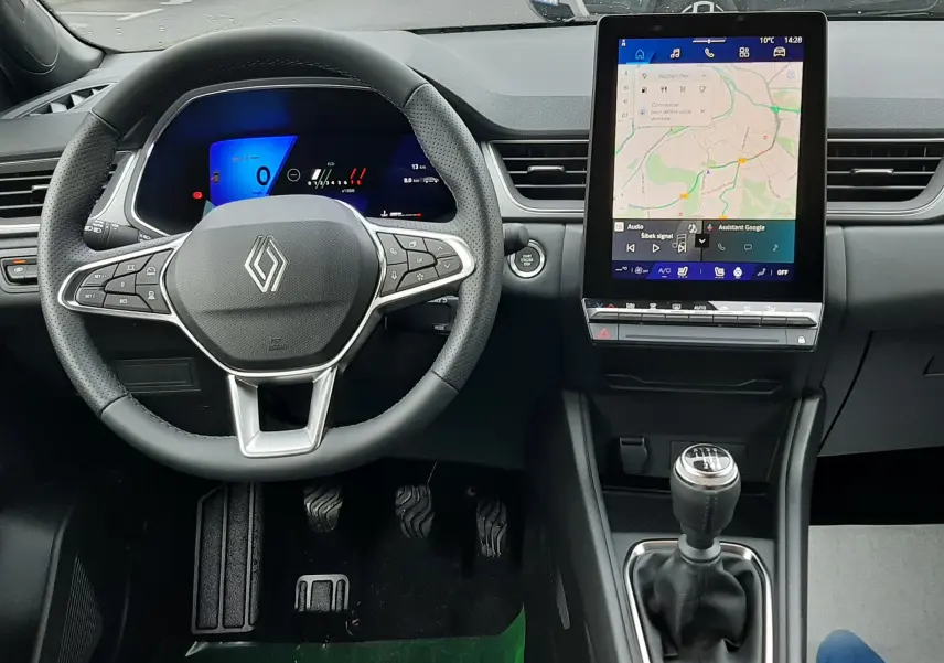 Vue intérieure avant du Renault Symbioz blanc nacré 2025, avec volant multifonction, écran tactile vertical et boîte manuelle.