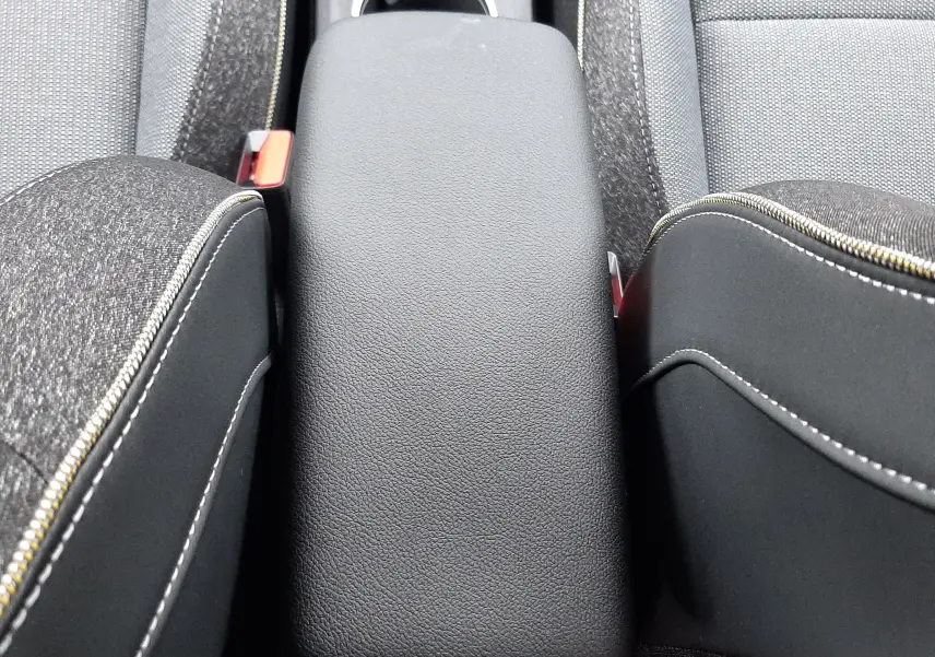 Vue rapprochée de l'accoudoir central noir entre les sièges avant gris foncé de la Renault Symbioz 2025.