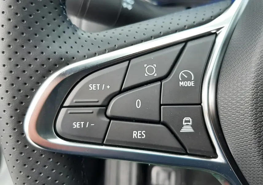 Gros plan sur les commandes multifonctions à gauche du volant perforé du Renault Symbioz blanc nacré, intérieur noir.