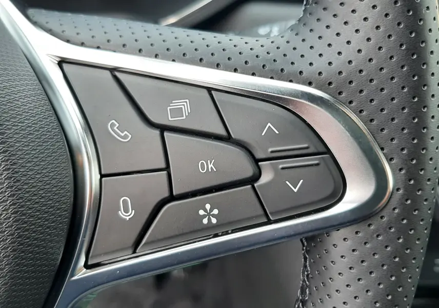 Gros plan sur les commandes multifonctions en plastique noir et chrome du volant perforé côté gauche du Renault Symbioz 2025.
