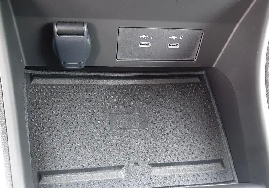 Gros plan sur la console centrale du Renault Symbioz blanc nacré, montrant deux ports USB-C et un espace de rangement antidérapant.